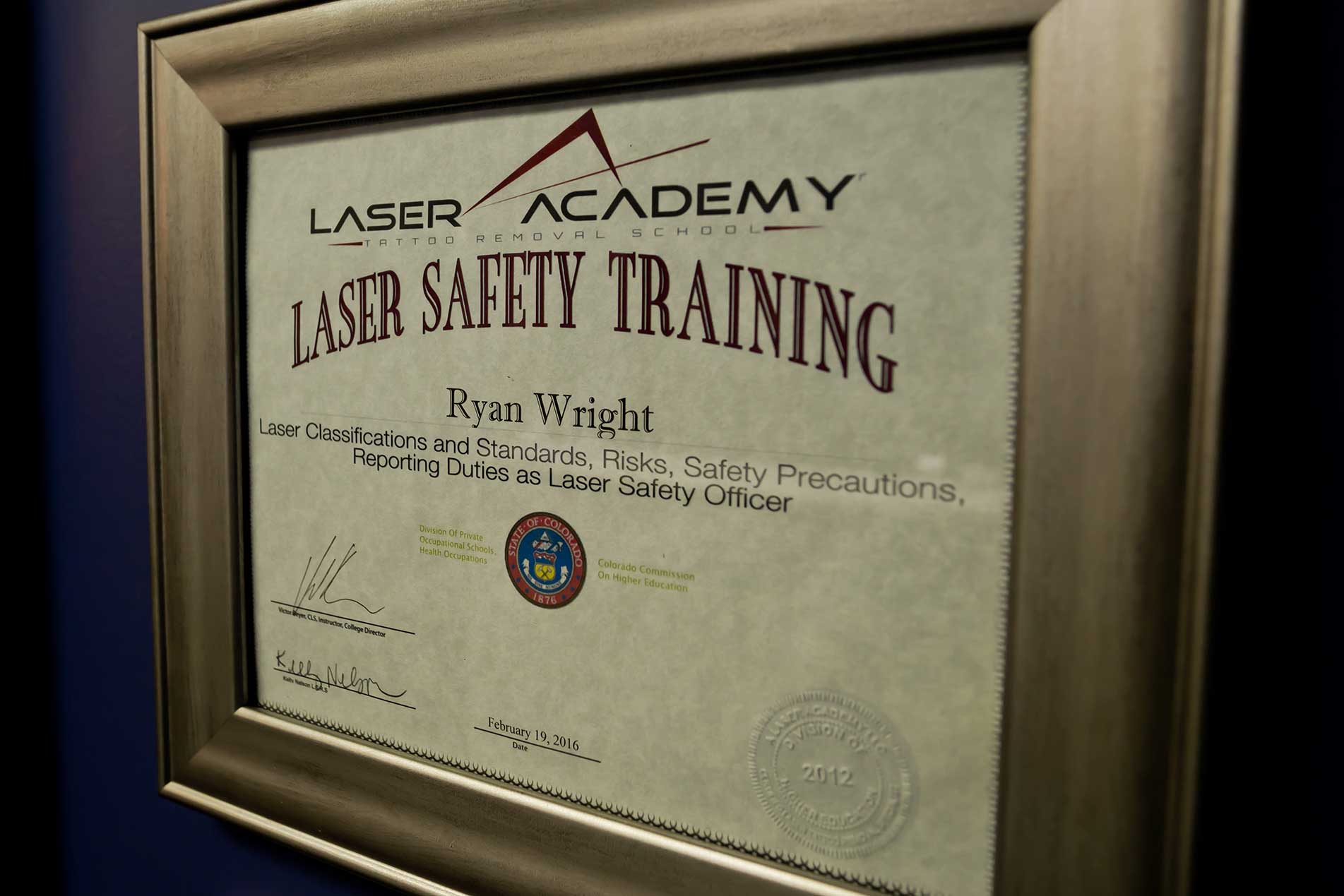 Framed laser safety certification hanging in the Ink Blasters clinic